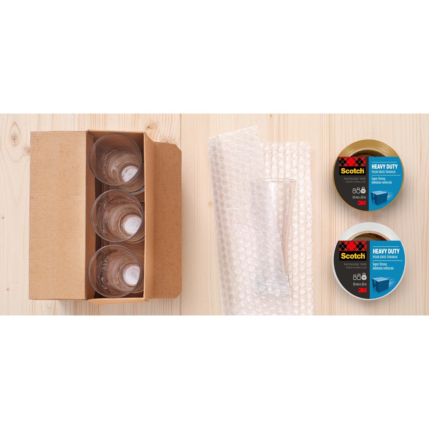 Ein offener Karton mit vier Glasbechern, Luftpolsterfolie und einem Scotch® Extra starkes Verpackungsklebeband (48 mm x 20,3 m) der 3M Deutschland GmbH steht auf einer hellen Holzfläche.