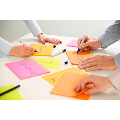 Tre persone scrivono su 3M Post-it® Super Sticky Notes in formato grande, a righe (101 x 152 mm), di 3M Deutschland GmbH. Sul tavolo bianco ci sono fogli colorati con parole come "Optional" e pennarelli non chiusi.