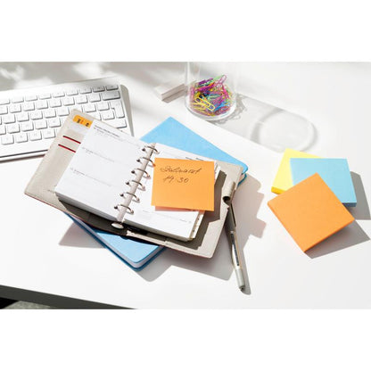 Un planner con una penna si trova su una scrivania accanto a una tastiera, graffette e una pila di Post-it® Notes (76 mm x 76 mm, 100% PEFC) della 3M Deutschland GmbH. Un foglietto arancione con la scritta "Dentista 4:30" è attaccato al planner.