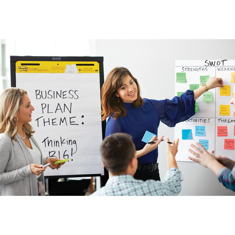 Quattro persone si incontrano in una stanza. Una donna indica un foglio Post-it® Super Sticky Z (76x76 mm, 3M Deutschland GmbH) su un diagramma SWOT. Un'altra è accanto a un flipchart con la scritta "Business Plan Theme: Thinking Big!".