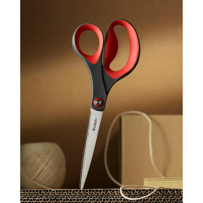 Un paio di forbici di precisione rosse Scotch™ di 3M Deutschland GmbH è incollato in posizione verticale su cartone ondulato, sullo sfondo si vedono corde beige e una scatola di cartone.